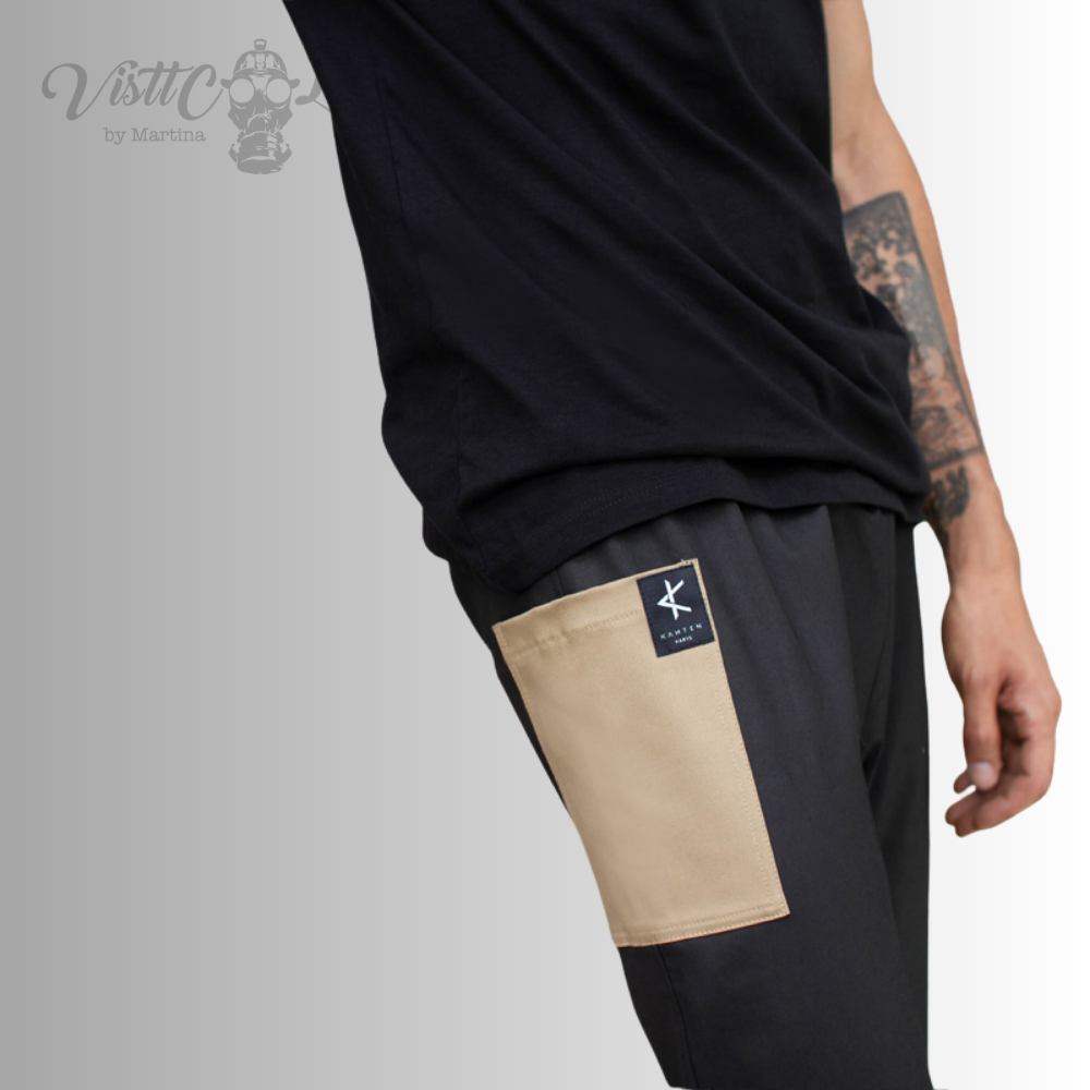 Primer plano lateral de un modelo usando el pantalón Taitsu negro, destacando el bolsillo superior en bloque de color arena y la etiqueta visttcool.