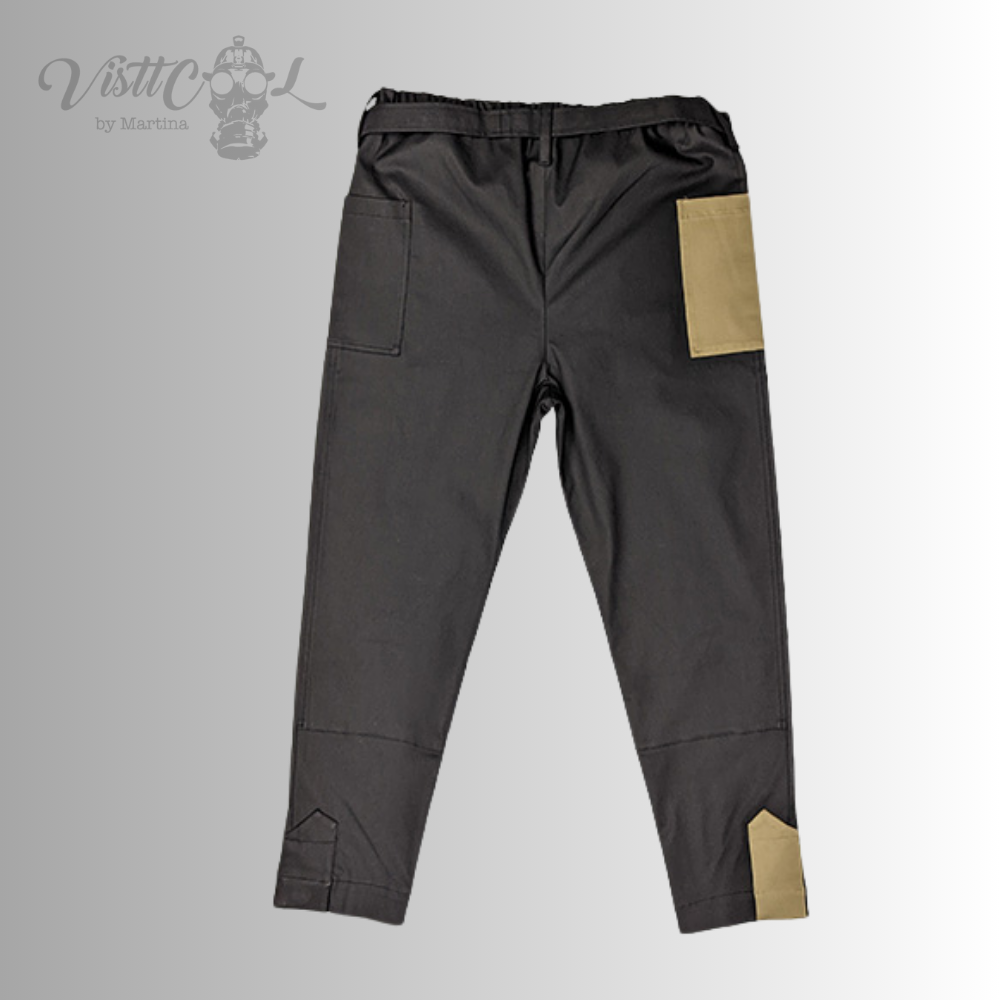 Vista trasera del pantalón negro Taitsu, resaltando el corte y las pestañas de ajuste beige con imanes en la zona de los tobillos.